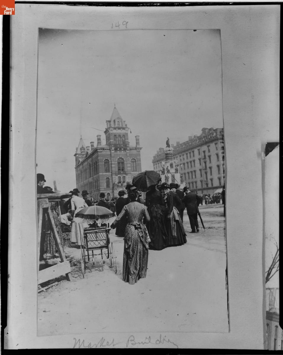 Group of Women, One with a Baby Carriage, in front of the Central Market Building, Detroit, Michigan, circa 1890 / negative Small crowd of people, one with a baby carriage, on a street