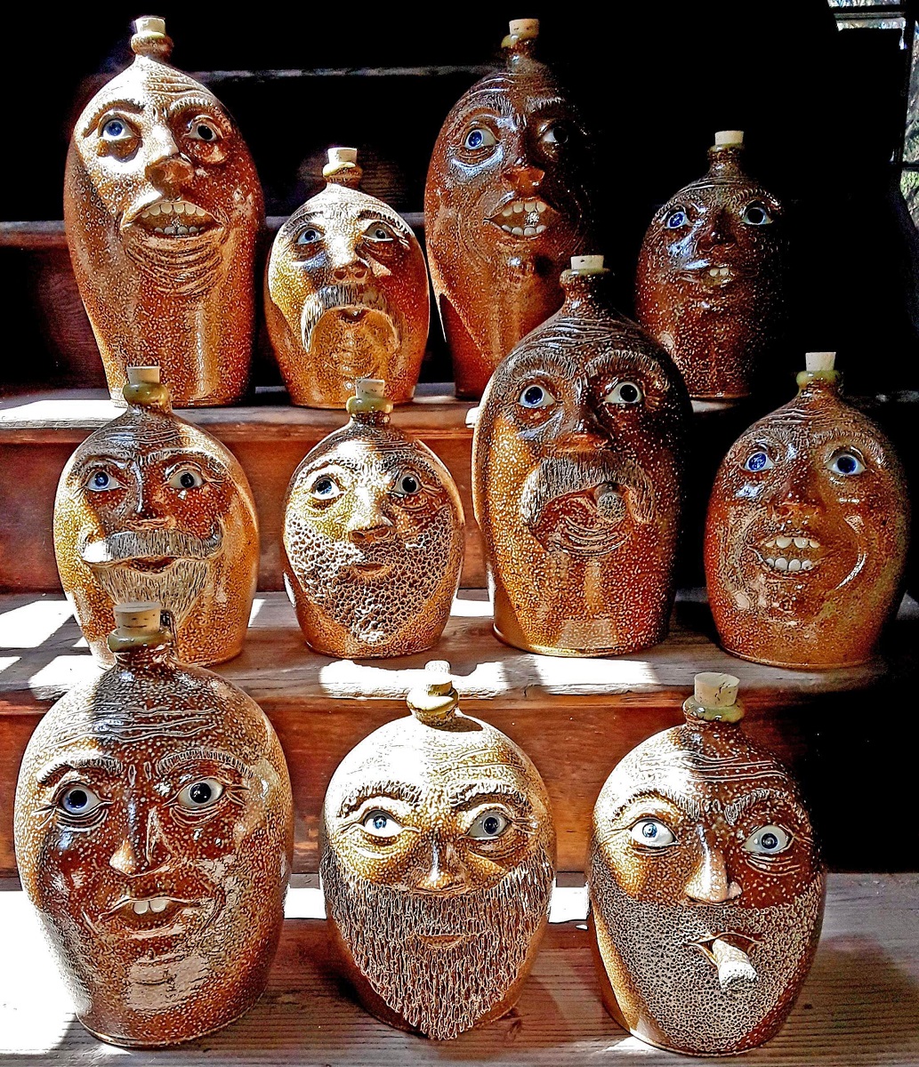 Pottery jugs featuring whimsical faces Eight orange pottery jugs topped with corks feature a variety of whimsical faces