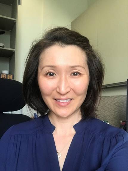 Woman with medium-light skin and dark hair in a blue shirt