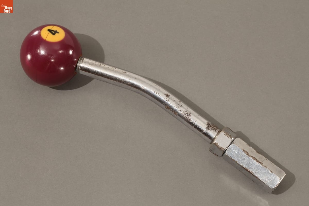 Slightly bent metal rod topped with with maroon ball with number "4" in a gold circle