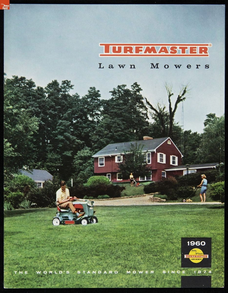 Image of red house behind large green lawn with man on riding lawnmower