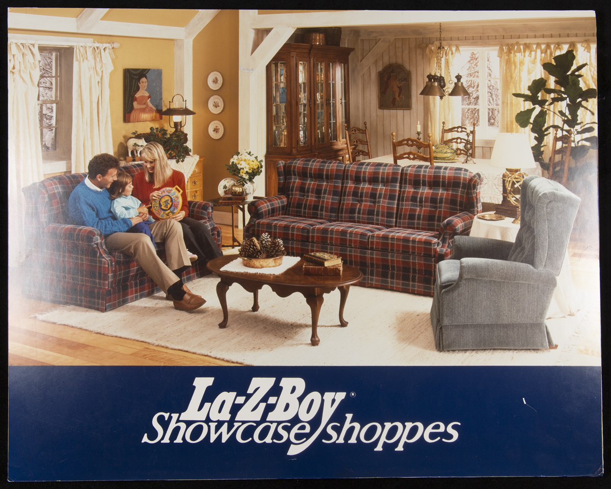 La-Z-Boy Showcase Shoppes, 1980-1988 La-Z-Boy Showcase Shoppes, 1980-1988 Living room with woman, man, and child on couch, with text “La-Z-Boy Showcase shoppes” below