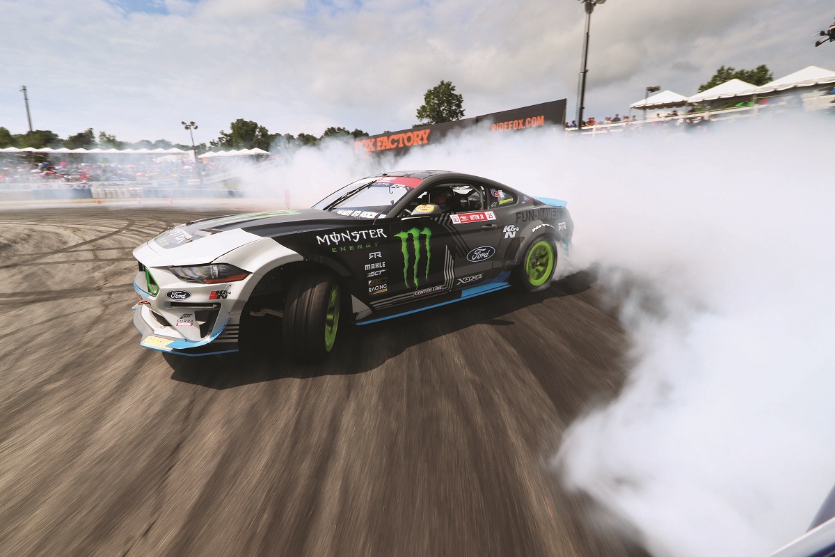 Gray and white race car turns on racetrack and trails smoke