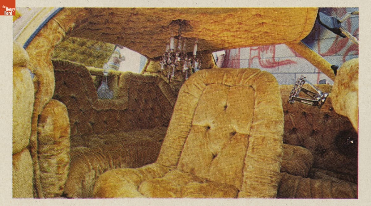 Car interior upholstered entirely in thick, mustard-yellow tufted velvet; a chandelier hangs from ceiling