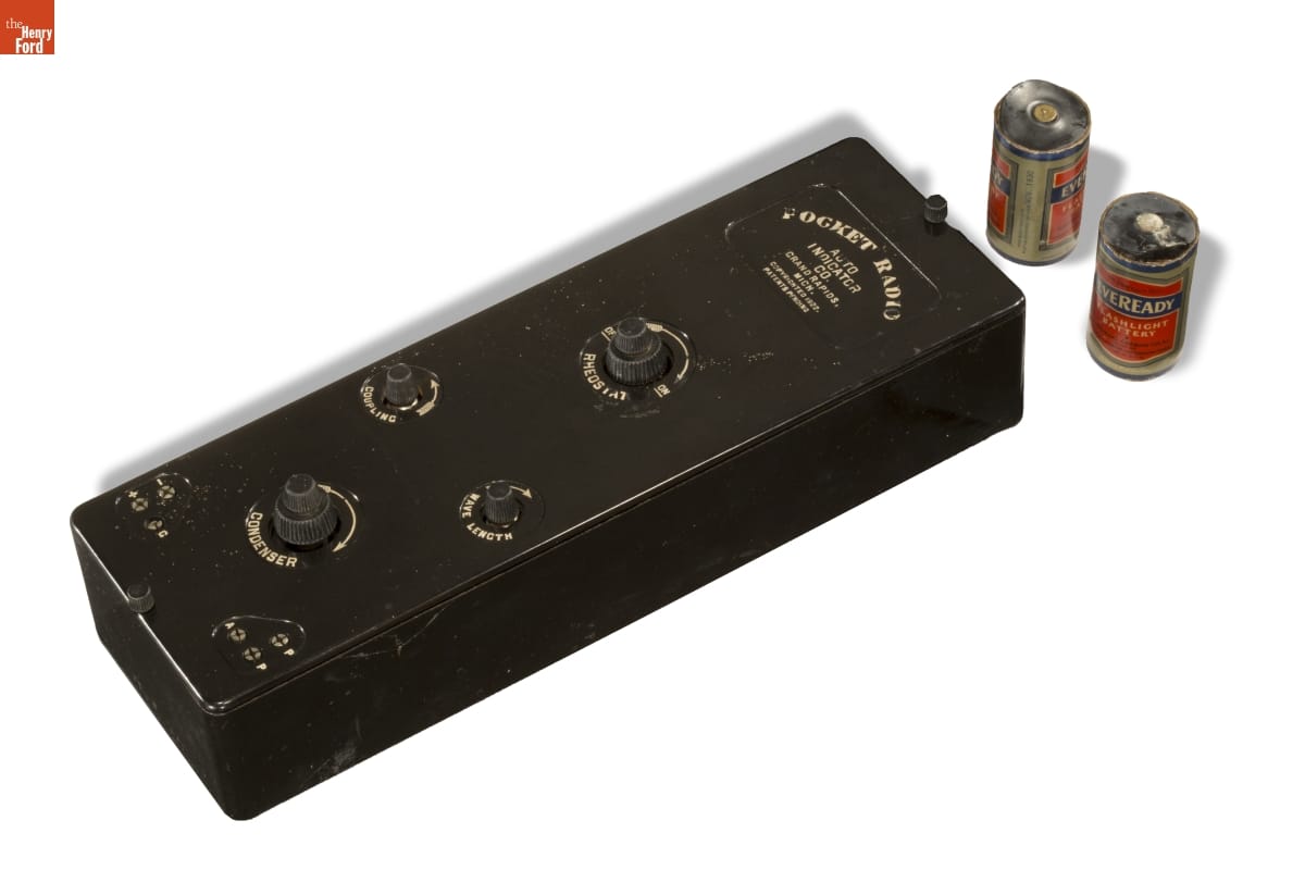 Black box with knobs and text; two batteries at side