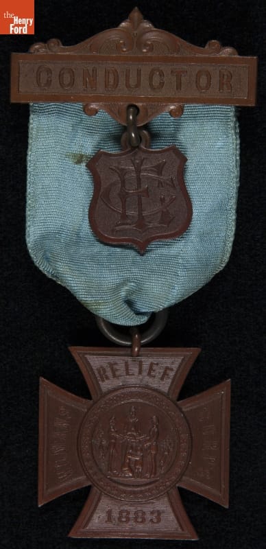 Metal and fabric badge, with cross-shaped piece containing text underneath a fabric arch