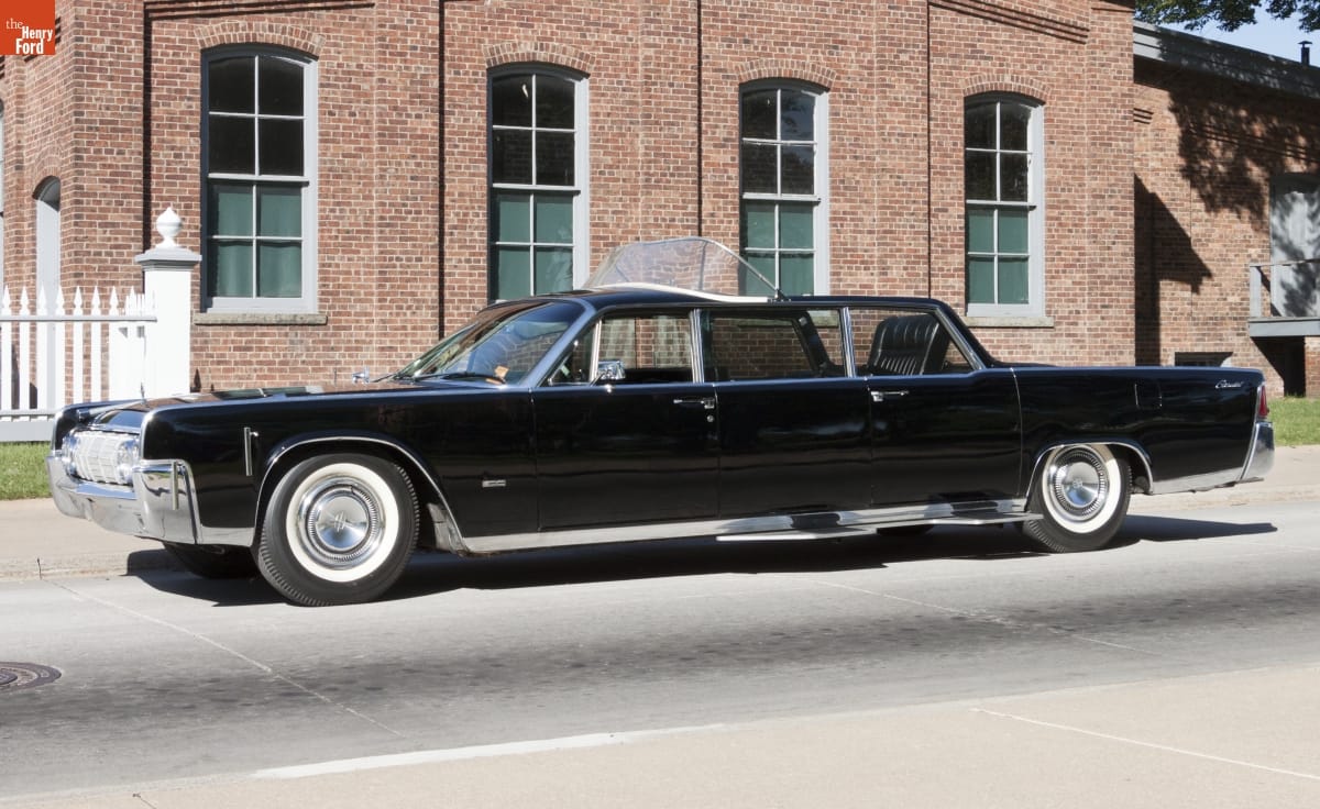 Black limousine parked outside a red brick building
