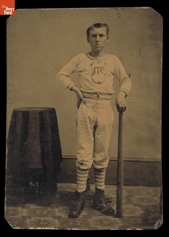 Black-and-white image of a man in a baseball uniform, holding a bat