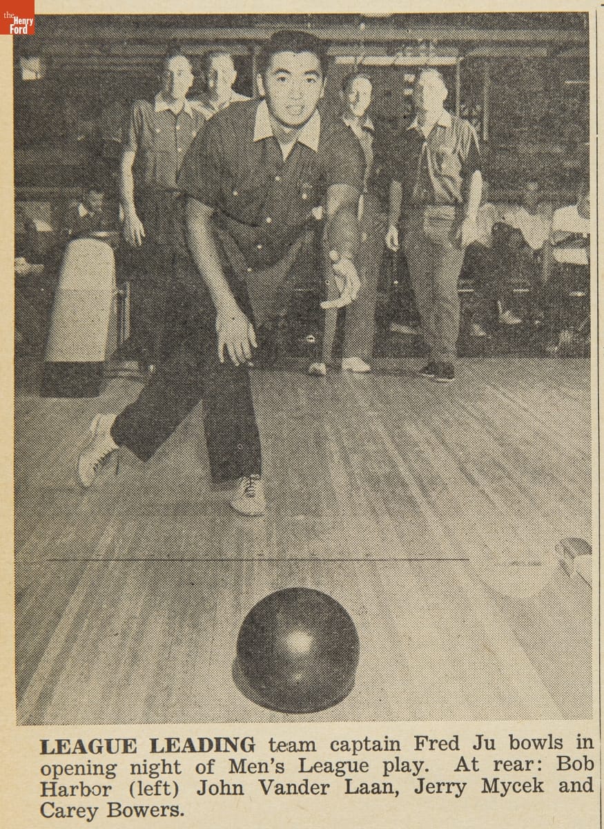 Man in bowling shirt and shoes and black pants rolls a bowling ball toward the camera; also contains text caption