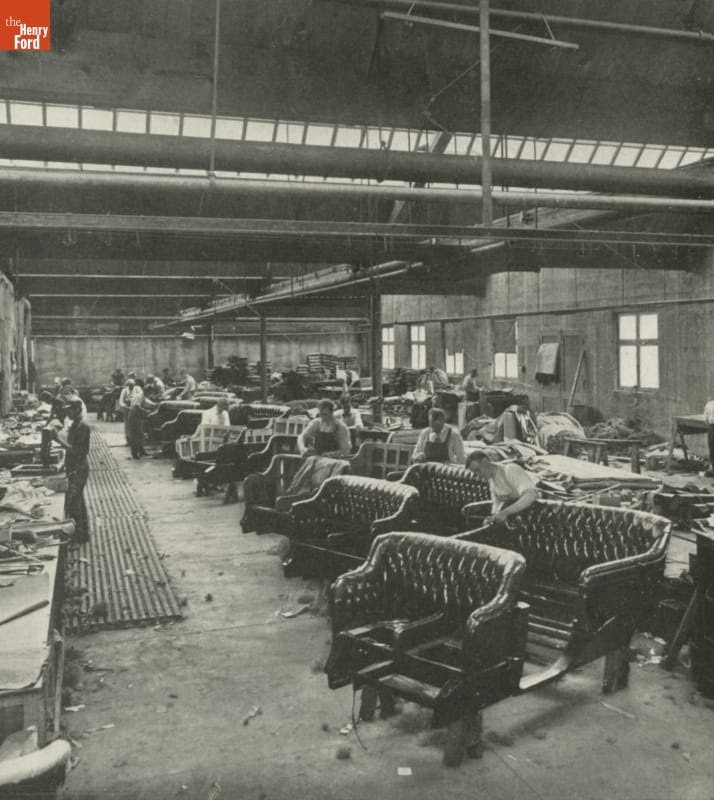 Inside factory with many car bench seats and people working on them