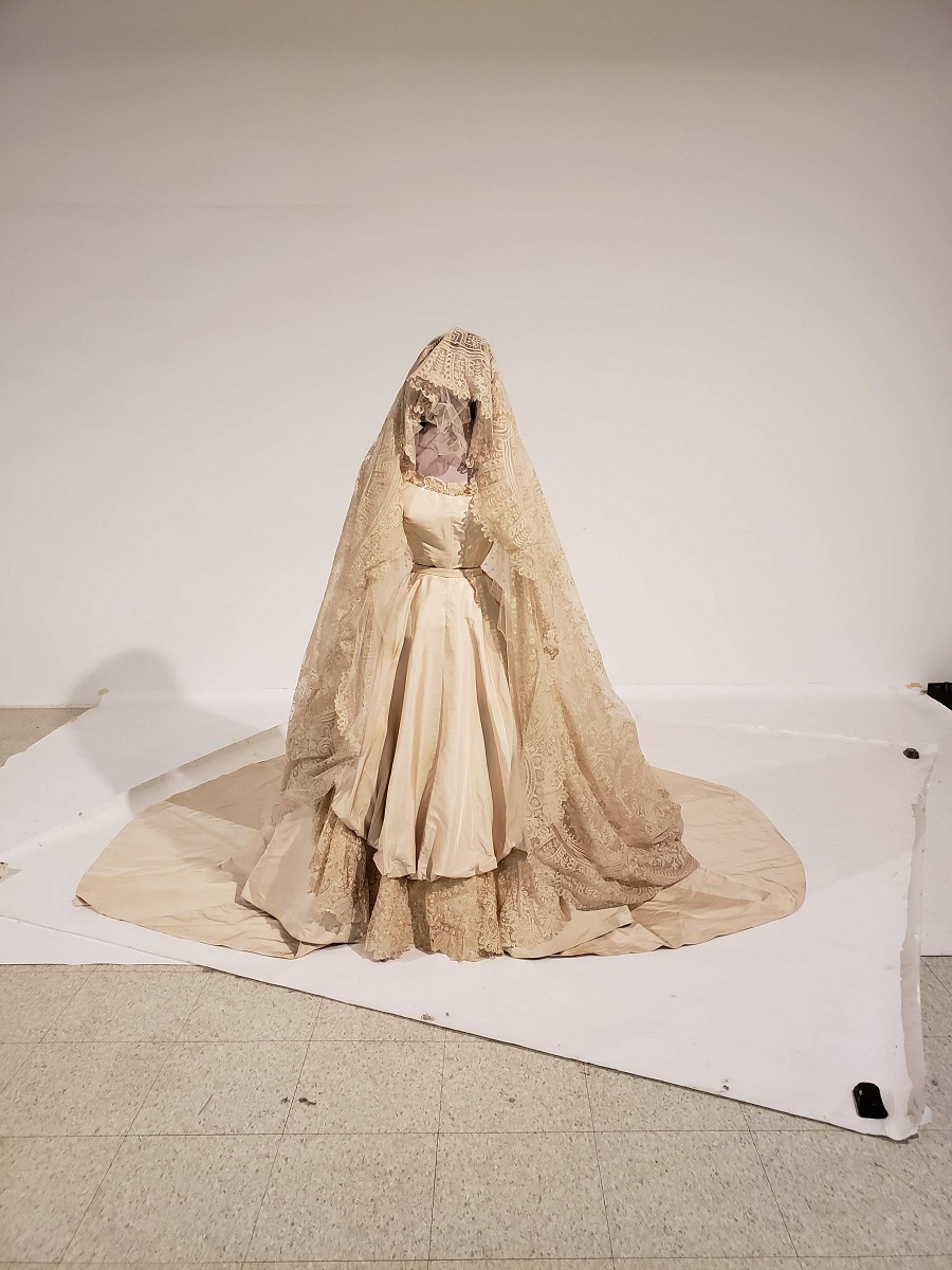 Photographing Elizabeth Chambers Firestone's wedding dress in the old studio Wedding dress and elaborate veil/headdress on a mannequin standing on white paper