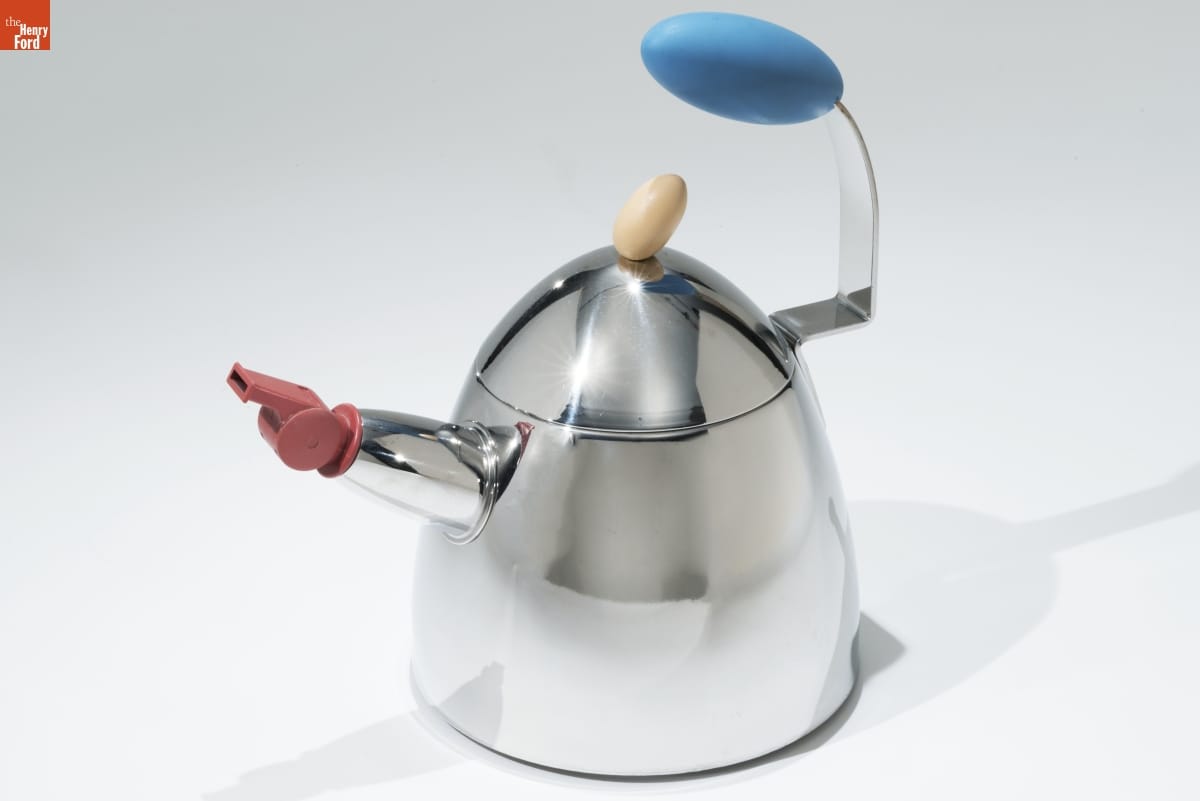 Dome-shaped silver teakettle with blue handle on one side and spout on other side topped with a red whistle