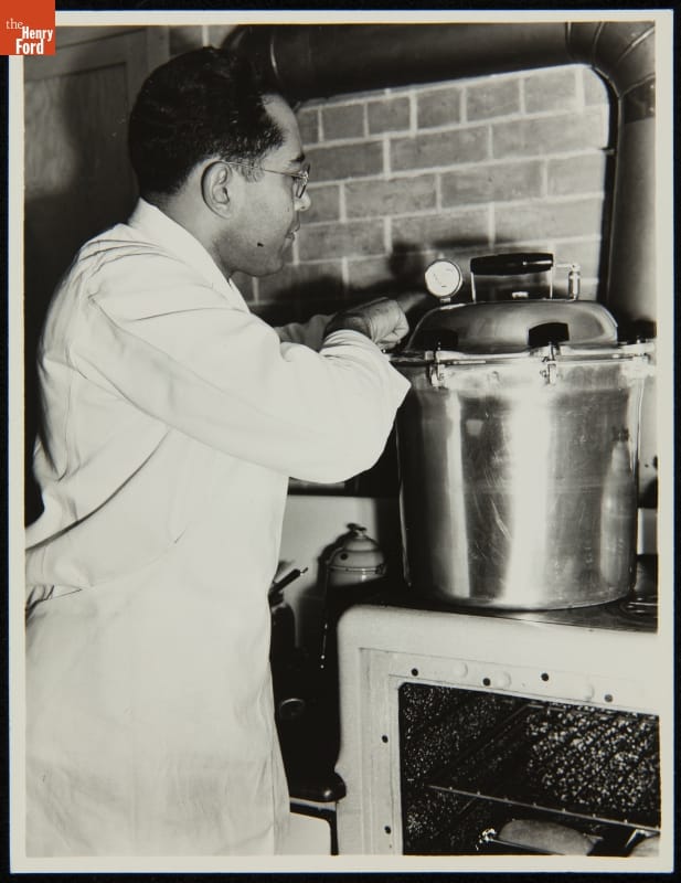 Man in white apron works at a pressure cooker