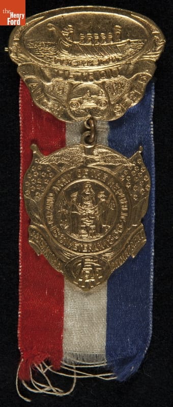 Red, white, and blue ribbon behind gold medallion with intricate pattern; also contains text