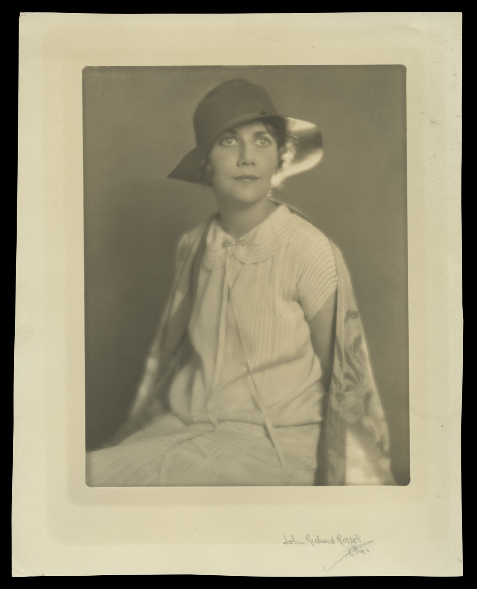 Black-and-white photo of seated woman in dress and hat