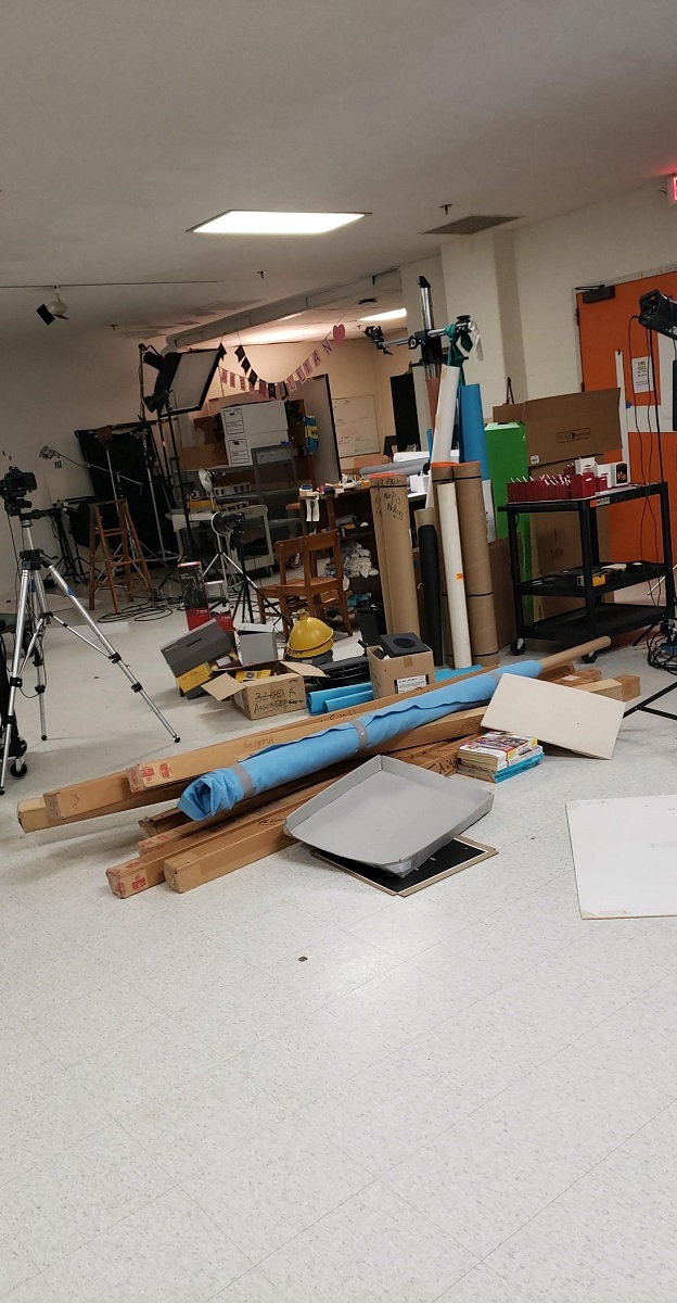 Piles of items to donate, sell, or discard Room cluttered with rolls of material, boxes, and other items in a pile on the floor