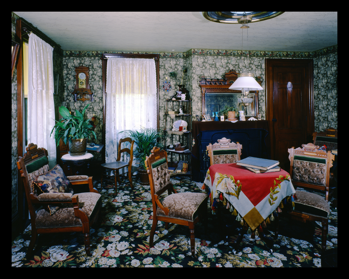 Parlor inside Firestone Farmhouse in Greenfield Village, July 1985 Room crowded with furniture and with busy floral carpeting and wallpaper