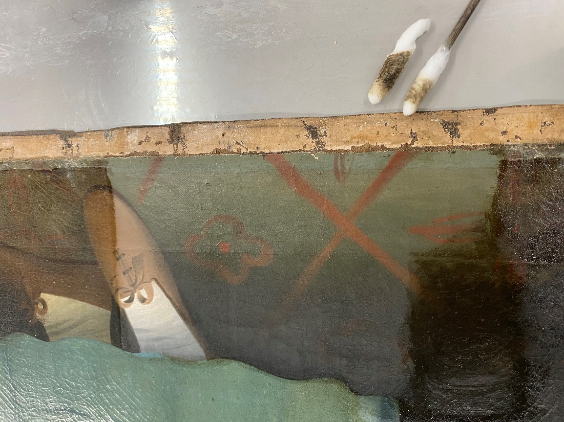 Bottom of painting canvas showing floor and shoes, with one portion lighter than the remainder; tools nearby