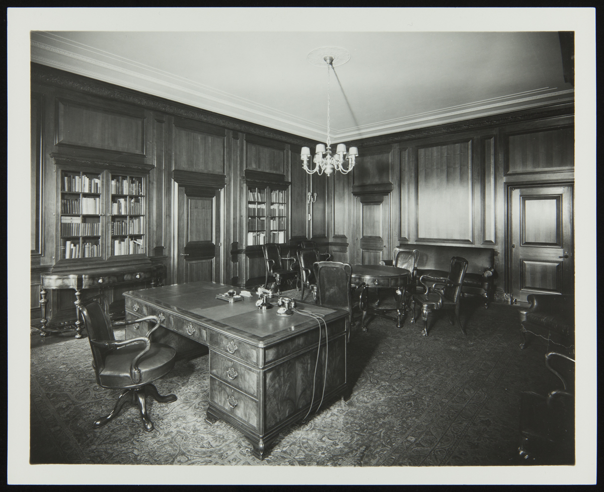 Interior of office with wood paneling, wooden furniture, and built-in bookshelves
