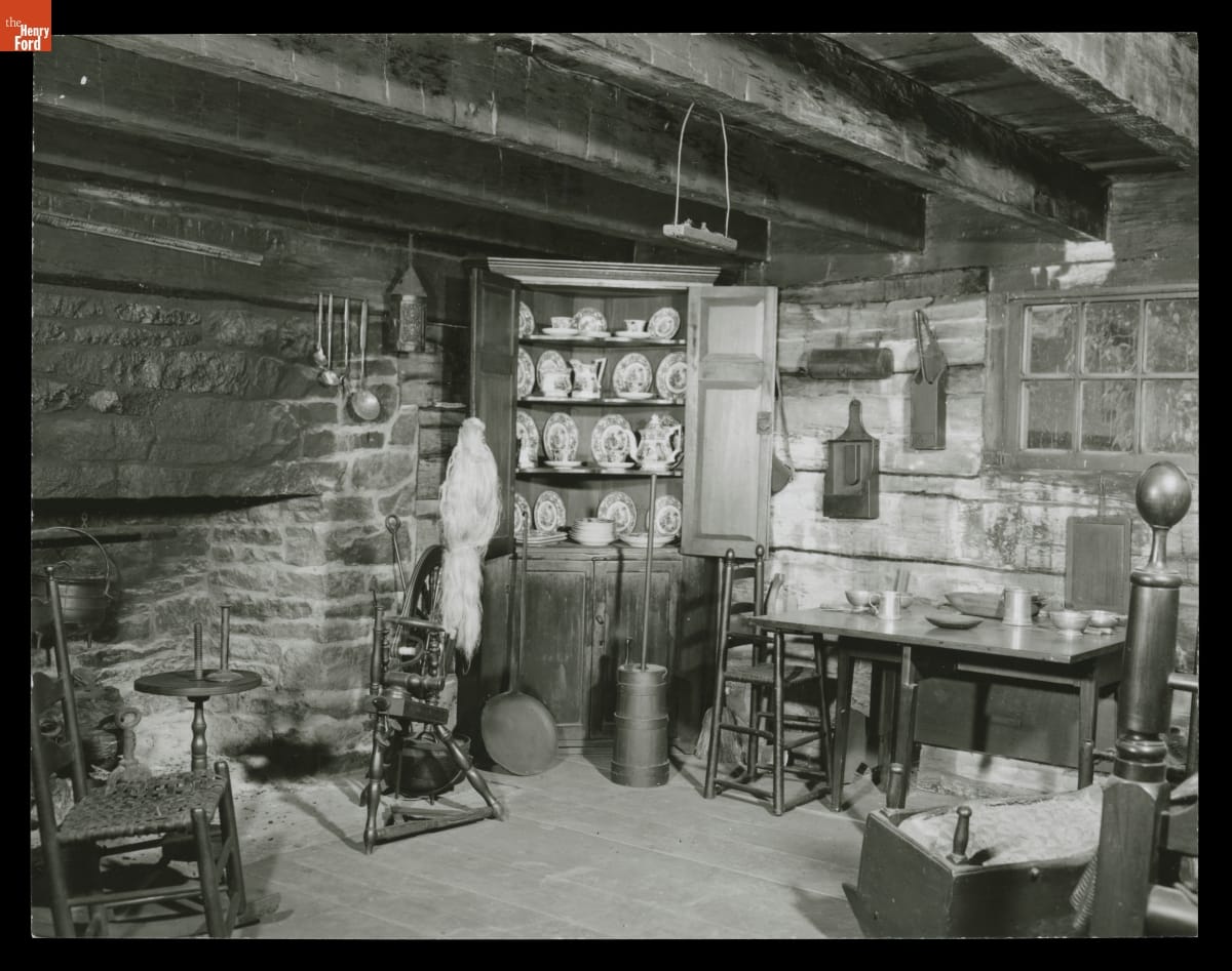Interior of room building with low beamed ceiling, large stone fireplace, and various furniture