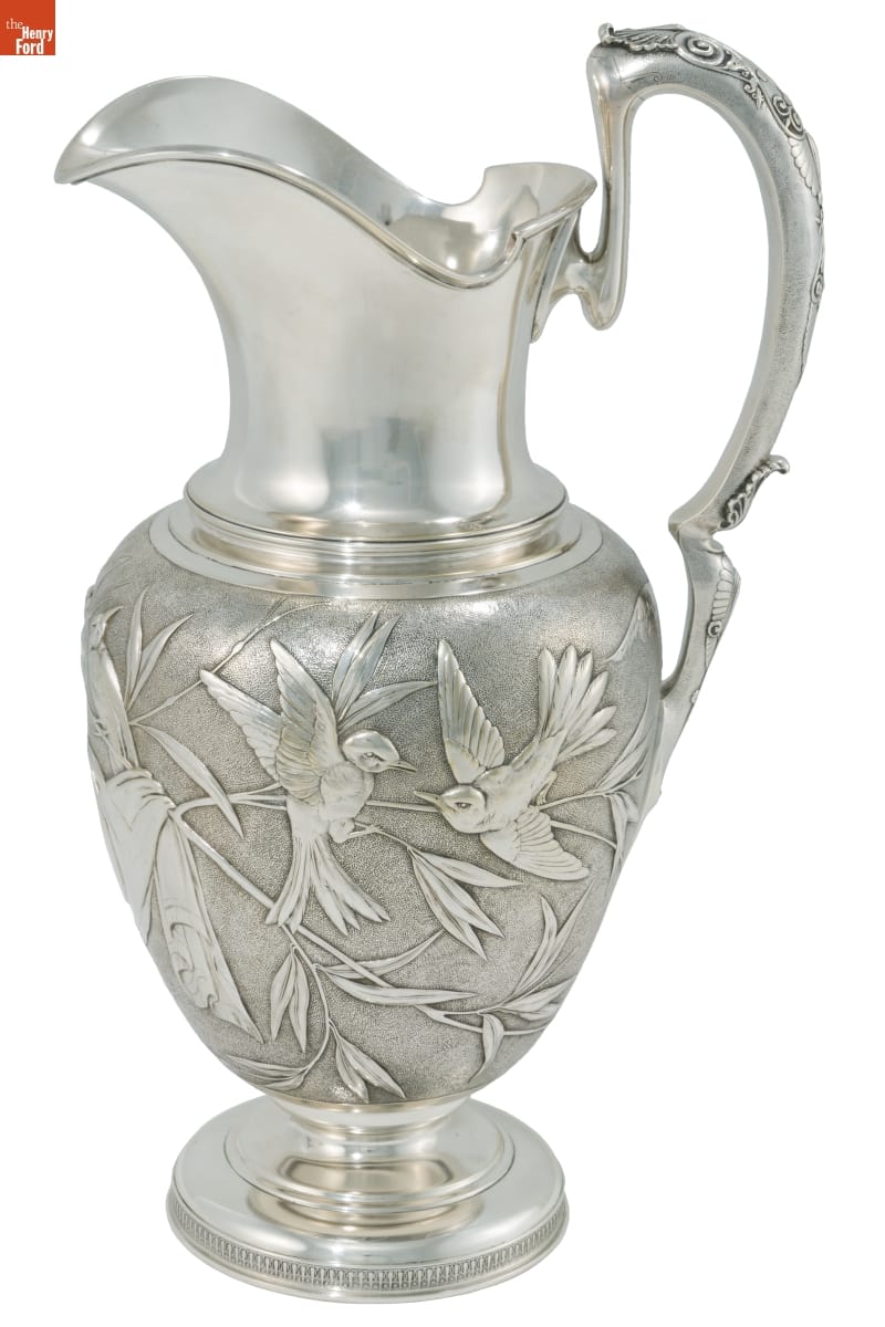 Elaborate, tall silver pitcher with engraved birds and foliage on body