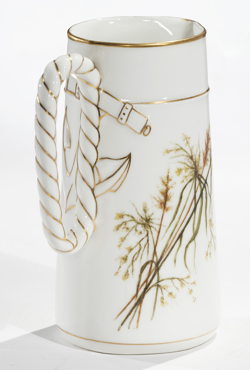 White pitcher with decorative gold striping on handle and at top and botanical design on side