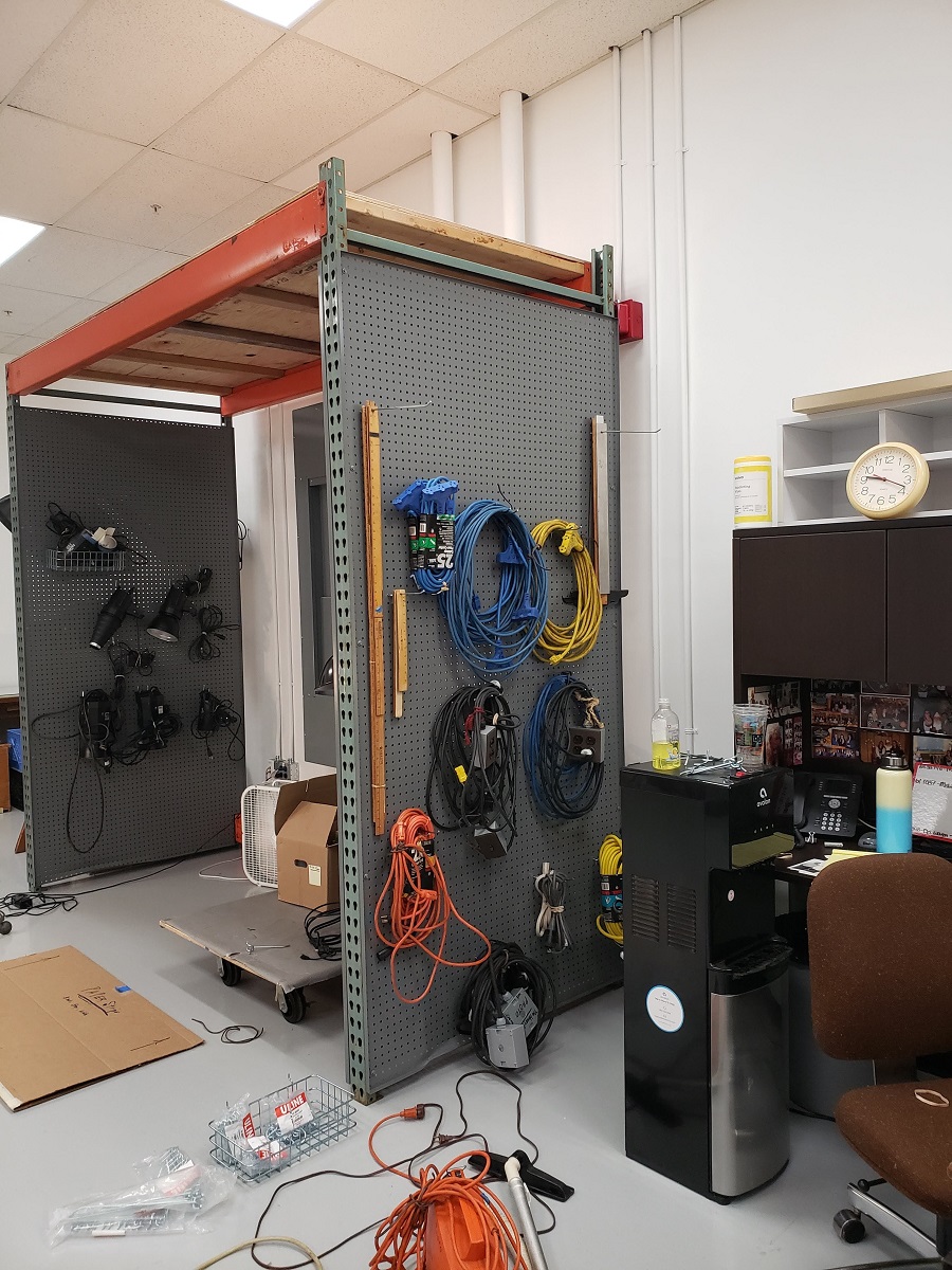 Pallet rack and pegboard Cluttered room with pallet racking covered in pegboard with cables and wires hanging on it