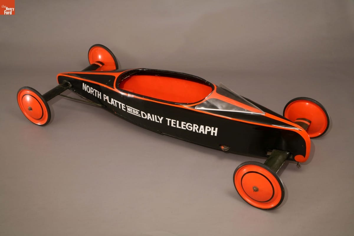 Teardrop-shaped black-and-orange wheeled vehicle with text along side