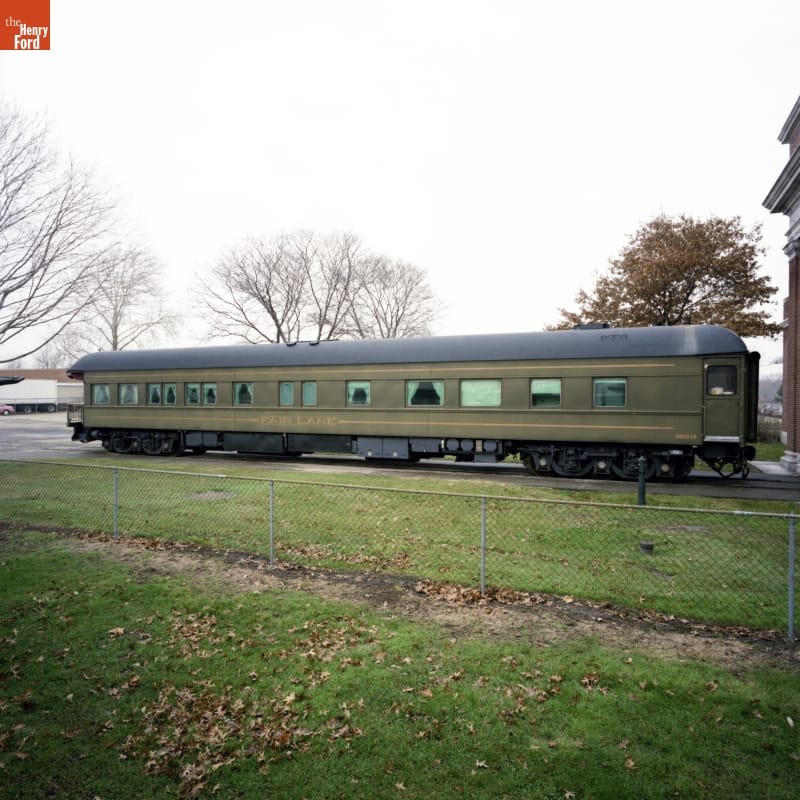 Drab green railcar sitting on railroad tracks 