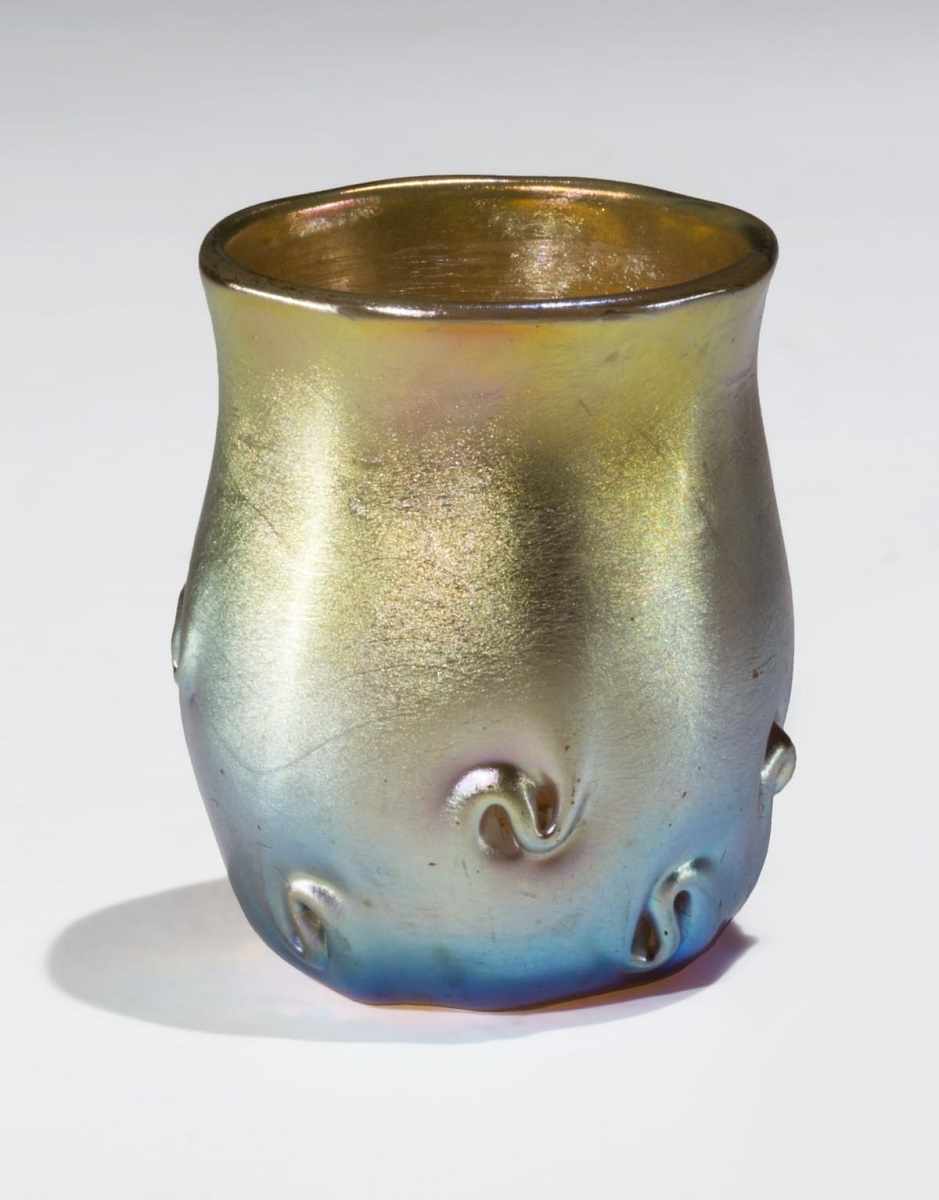 Iridescent glass container with s-shaped swirls, with color morphing from blue at the bottom to gold at the top