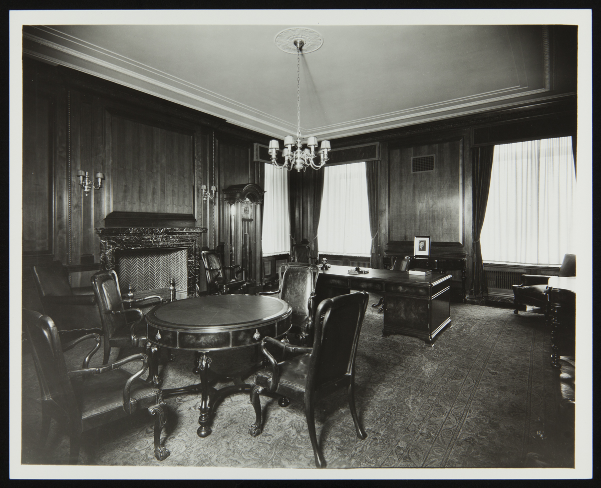 Black-and-white photo of office with wood paneling and wooden furniture