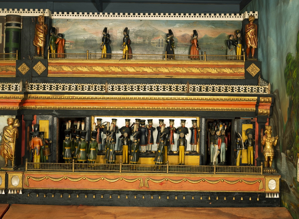 Wooden platform with two carved scenes with human figures, one above the other