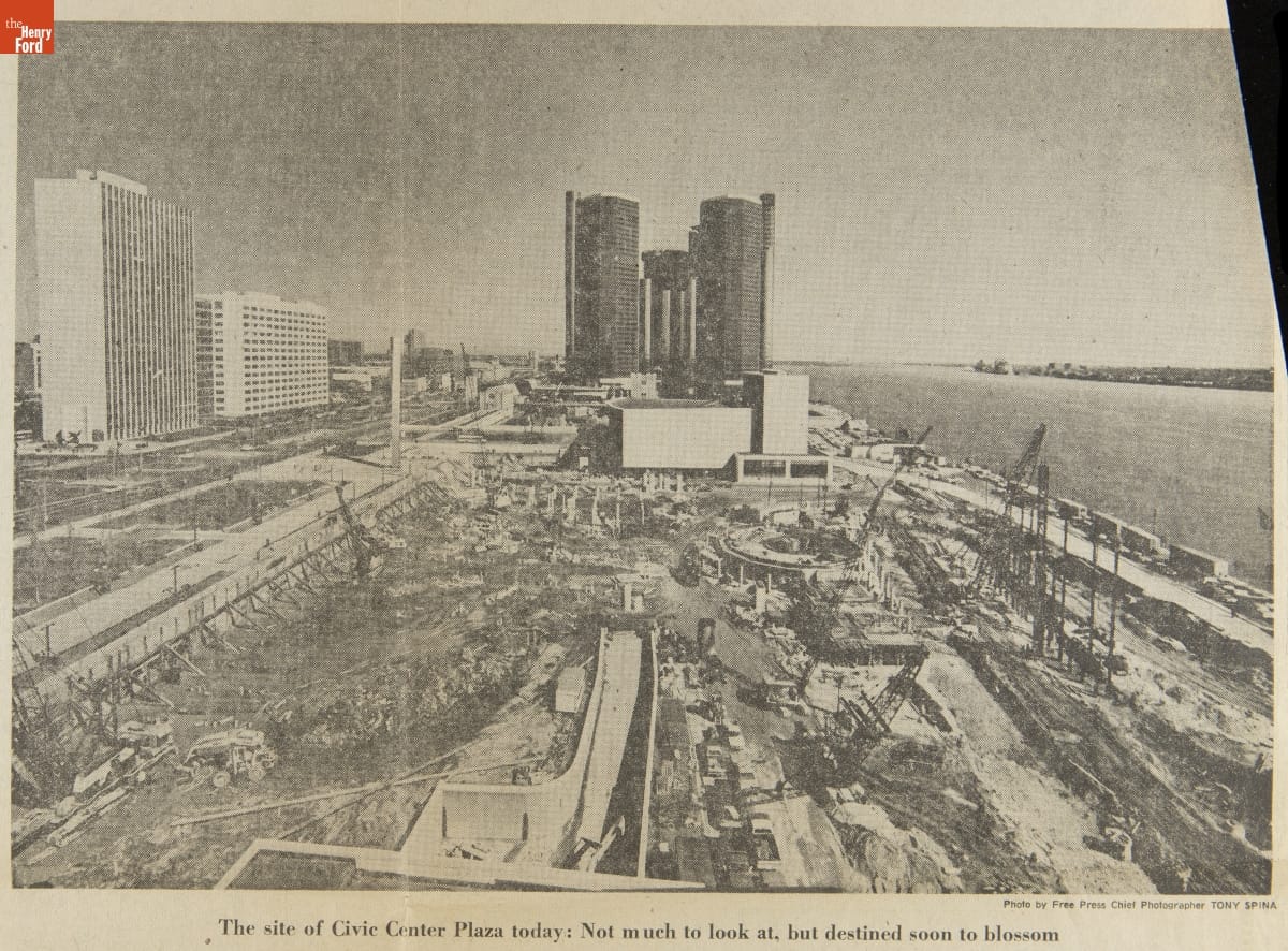 Image of construction site by river with tall buildings behind and to the side of it