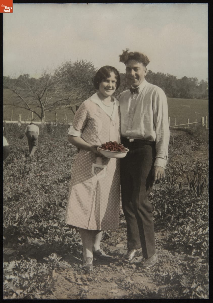 Ella and Edward Posorek in a Strawberry Field, circa 1932 Partially colorized black-and-white photo of a woman and man standing next to each other in a field; the woman holds a bowl of strawberries