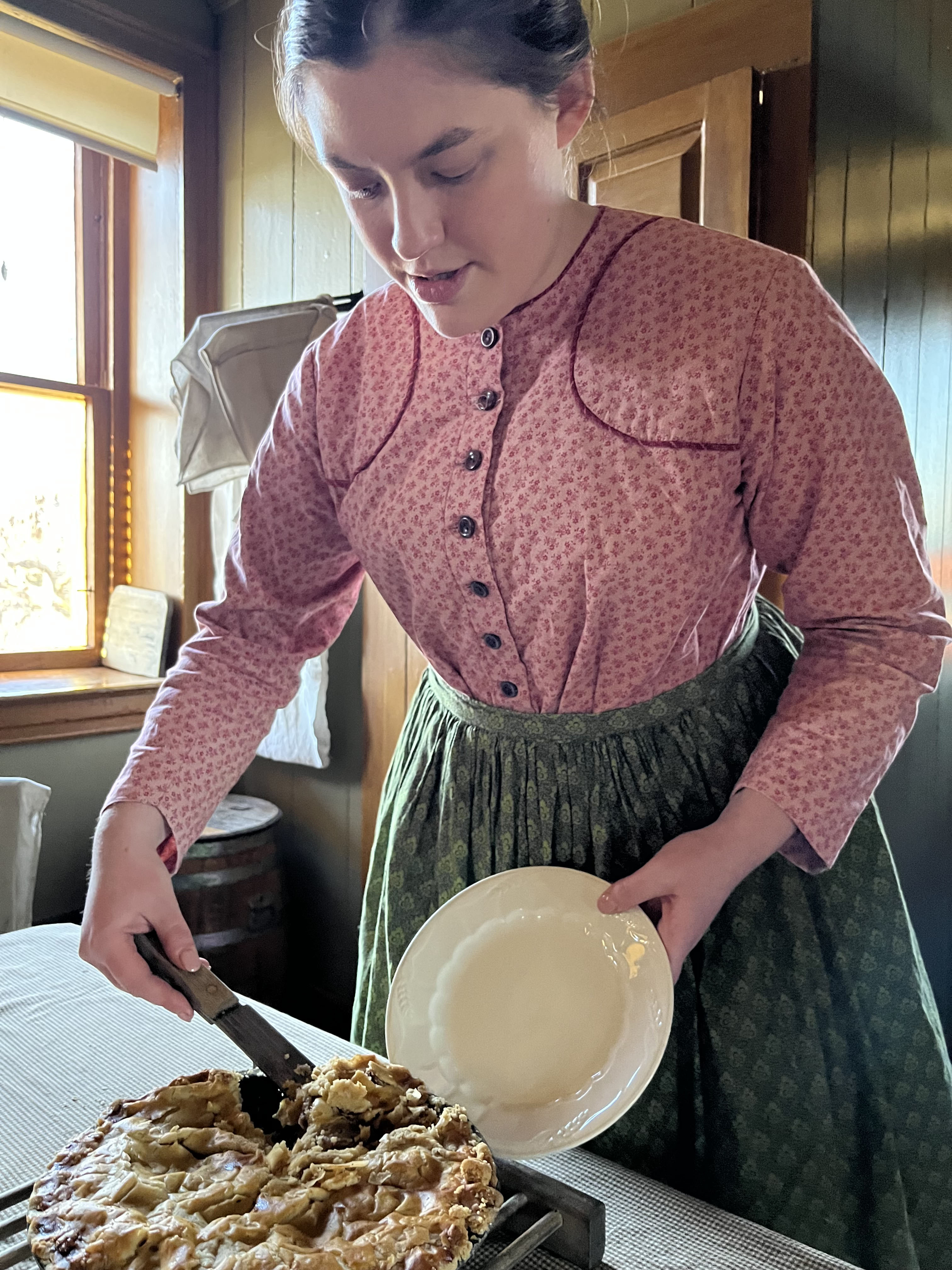 A presenter serves apple pie at Firestone Farm in Greenfield Village.