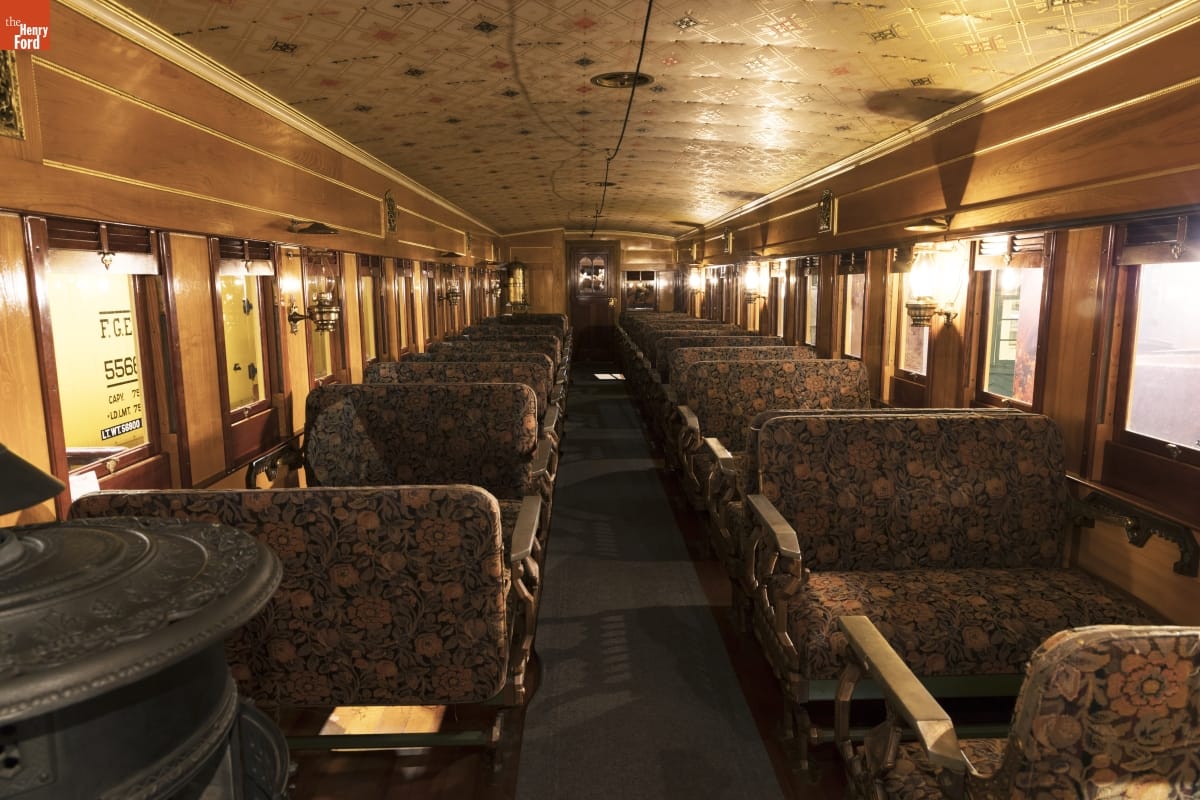 Interior of train car with wooden walls and ceiling and floral upholstered bench seats